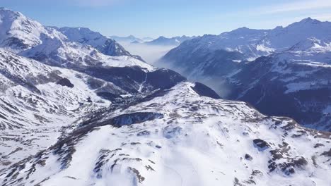 drone-reveal-of-Italian-alps-in-winter,-lots-of-snow,-valley-in-the-background,-tilt-up