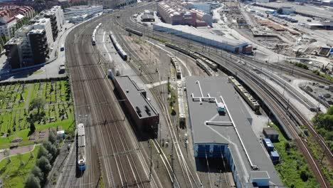 Aerial-flyover-of-tram-passing-through-Gothenburg-rail-yard-and-tracks
