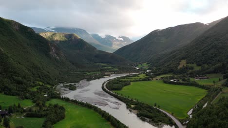 River-passing-through-narrow-mountains-and-beautiful-green-scenery-in-Norway-drone-shot