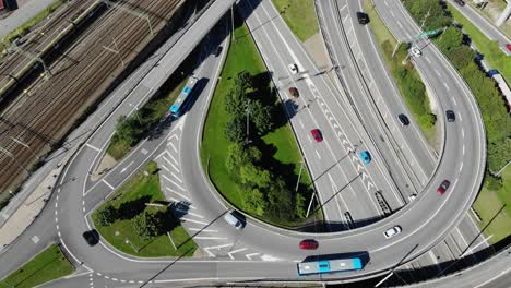 Aerial-view-overlooking-traffic-on-a-highway-intersection-and-railway,-sunny-day,-in-Sweden---high-angle,-drone-shot