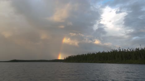 Herrlicher-Himmel-über-Einem-See-Mit-Einem-Regenbogen,-Der-Durch-Die-Wolken-Dringt
