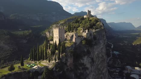 Helicopter-view-of-some-old-ruins-on-top-of-a-cliff-hillside-in-the-Italian-Dolomites,-Castello-di-Arco,-Riva-del-Garda