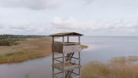 Aerial-drone-flying-above-wooden-watchtower-Vortsjarv-lake-in-Estonia,-Europe
