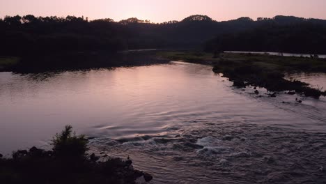 Schöner-Fluss,-Der-Bei-Sonnenuntergang-Durch-Die-Wildnis-Der-Landschaft-Fließt,-Luftaufnahme