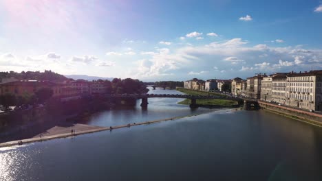 Aerial-view-flying-fast-above-Arno-River-and-city-on-a-sunny-day-in-Florence-in-Italy-in-4k