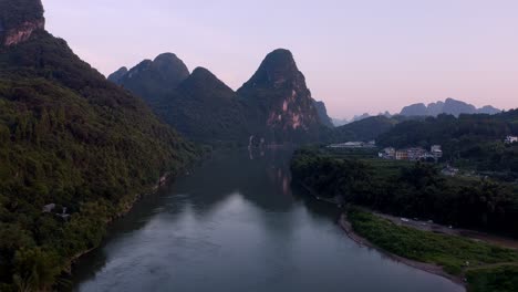 Beautiful-river-flowing-through-Asian-karst-mountain-landscape-at-sunset,-aerial