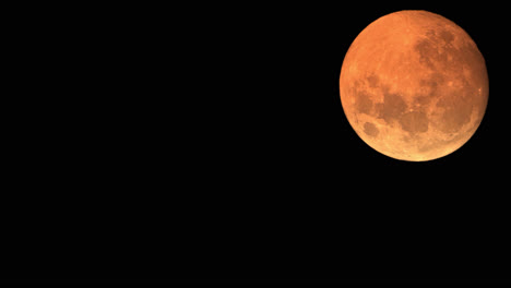 Closeup-Detail-Of-Full-Moon-Setting,-Illuminated-In-The-Night-Sky