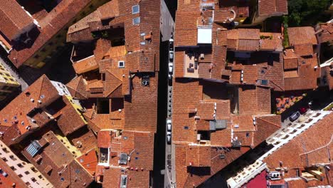Top-down-view-flying-above-roofs,-roads-and-city-on-a-sunny-day-in-Florence-in-Italy-in-4k