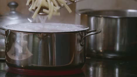 Cocinar-Y-Remover-Pasta-Ziti-Con-Una-Espátula-De-Madera-En-Una-Olla-De-Acero-Inoxidable-Con-Agua-Hirviendo-Y-Burbujas-Encima
