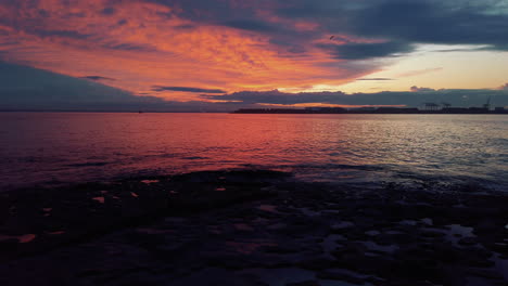 Ruhiger-Sonnenuntergang-Mit-Roten-Und-Orangefarbenen-Wolken,-Die-Sich-Auf-Der-Oberfläche-Des-Ozeans-Reflektieren,-Langsam