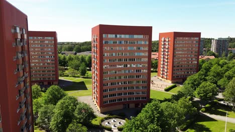 Drone-Flying-Through-Contemporary-Residential-Buildings-Against-Bright-Blue-Sky-In-Västra-Frölunda,-Gothenburg,-Sweden---elevated-shot