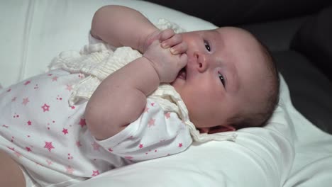 Baby-Lutscht-Glücklich-An-Den-Fingern,-Während-Es-Auf-Dem-Bett-Liegt