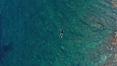 Aerial-dolly-shot-of-a-lone-swimmer-off-the-coast-of-Losinj-island,-Croatia