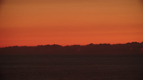 Timelapse-of-amazing-orange-red-sunset-at-sea-with-grey-clouds-above-horizon