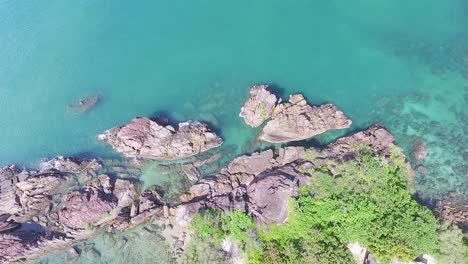 Tropical-Koh-Chang-turquoise-ocean-dense-woodland-rocky-coastline-birdseye-rising-aerial-view-Thailand