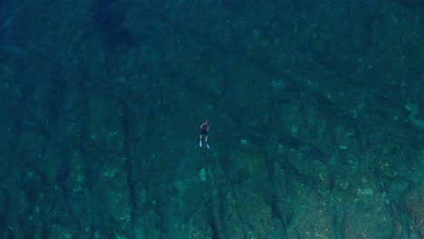 Aerial-dolly-shot-of-a-lone-swimmer-off-the-coast-of-Losinj-island,-Croatia