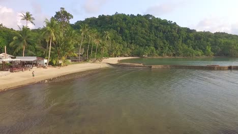 Drohnen-Dolly-Aufnahme-Eines-Kleinen-Tropischen-Strandes-Mit-Kajak-Und-Palmen-Und-Einem-Resort-In-Thailand
