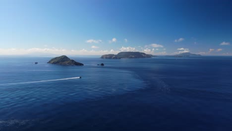 Leitet-Luftdrohnenflug-über-Den-Ozean-In-Richtung-Inseln-Mit-Einem-Einzelnen-Boot-Am-Klaren-Tageshimmel-Weiter
