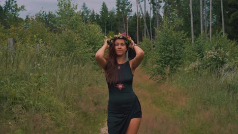 Carefree-female-hippie-putting-on-flower-headdress-in-middle-of-forest,-slowmo