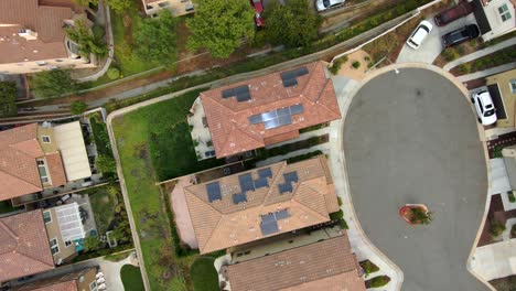 Solar-panels-on-home-rooftops-in-suburb-neighborhood,-aerial-top-down,-pull-up-view