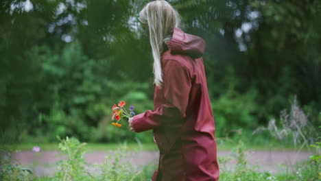 Side-View-Of-A-Dutch-Woman-Walking-At-The-Park-Holding-Freshly-Picked-Flowers-In-The-Netherlands---medium-slowmo-shot