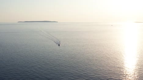 Aerial-tracking-shot-of-a-motorboat-speeding-around-off-the-coast-of-Losinj-island,-Croatia