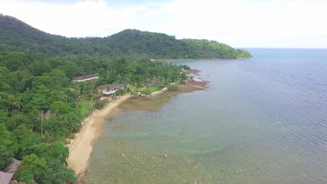 Aerial-shot-tilting-up-of-small-tropical-beach-with-small-hotel