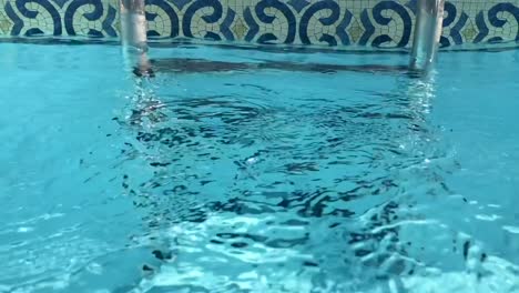 Transparent-closeup-view-of-swimming-pool-ladders-under-pellucid-crystal-clear-purified-water-flowing-downstream-in-slow-motion