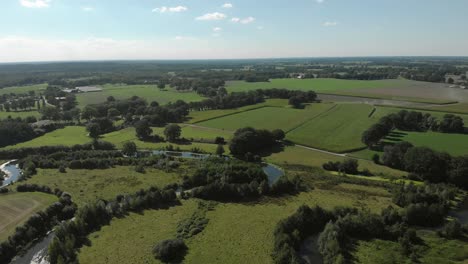 Aerial-view-of-Reggeland-with-the-river-Regge-in-Twente,-The-Netherlands,-meandering-through-the-Dutch-flat-landscape-with-its-farmlands-and-eventless-horizon