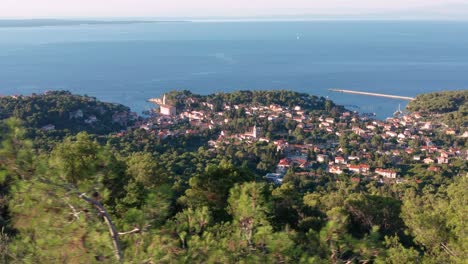Overflying-The-Lush-Green-Mountains-Overlooking-The-Seaside-Village-Of-Veli-Losinj-And-Northern-Adriatic-Sea-On-A-Sunny-Summer-Day-In-Losinj-Island,-Western-Croatia