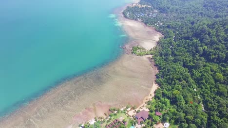 drone-tilt-shot-of-Island-tropical-coastline-with-beach-,-coral-reef-and-small-bungalow-resort