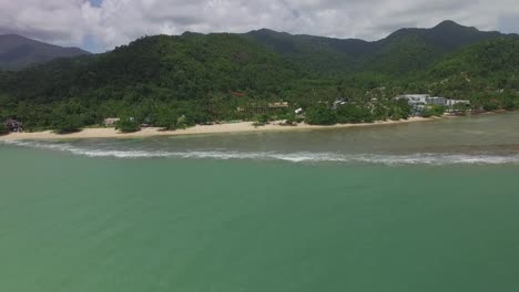 Aerial-view-heading-towards-Koh-Chang-paradise-island-resort-sandy-shore-over-turquoise-ocean-Thailand