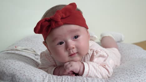Newborn-infant-baby-girl-lying-on-belly-supporting-her-head-with-hands,-back-and-neck-training