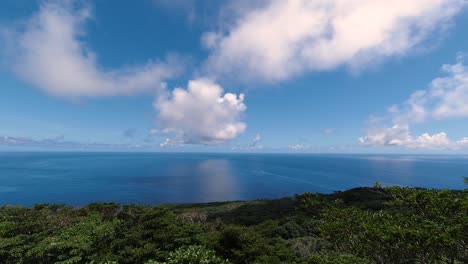 Sich-Schnell-Bewegende-Wolkenzeitraffer-über-Dem-Offenen-Blauen-Ozean-Mit-Reflexionen-Von-Wolken-Im-Wasser-Mit-Insel-Im-Vordergrund
