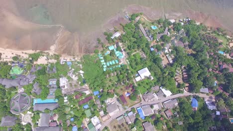 aerial-vertical-dolly-shot-of-small-Thai-village-with-small-bungalow-resorts-and-big-hotel-and-coastline