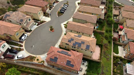Aerial,view-towards-Solar-panels-on-neighborhood-house-roofs,-cloudy-day,-in-Los-Angeles,-California,-USA---Tilt-down,-drone-shot