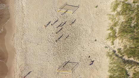Antenne:-Gruppe-Spielt-Fußball-Auf-Sand-Am-Strand-An-Einem-Sonnigen-Tag