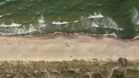 AERIAL:-Top-View-Shot-of-Isolated-Surfer-with-Wind-Kite-Standing-on-Beach-with-Rippling-Waves