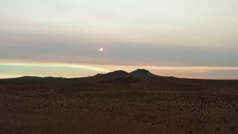 Die-Sonne-Ist-Hinter-Einem-Schleier-Aus-Dunst-Und-Rauch,-Der-Von-Kalifornischen-Waldbränden-In-Dieser-Luftaufnahme-Des-Sonnenaufgangs-über-Der-Mojave-Wüstenlandschaft-Zurückgelassen-Wurde