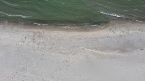AERIAL:-Descending-Top-View-Shot-of-Sandy-Beach-with-Seashore-and-Baltic-Sea-Seaside