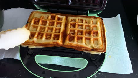 Removing-Hot-Waffles-From-The-Waffle-Maker-With-Plastic-Tongs---close-up-slow-motion