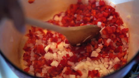 Sauteing-chopped-onions-and-red-bell-peppers-in-a-pot-on-the-stove---isolated-slow-motion