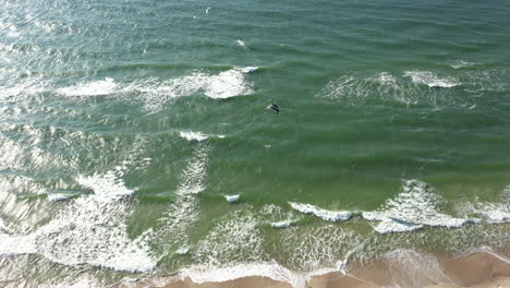 AERIAL:-Drone-view-of-the-Ocean-and-People-Engaged-in-Extreme-Sports,-Kitesurfing