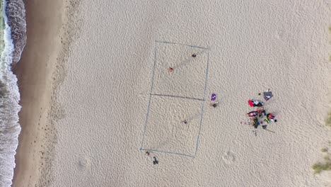 AERIAL:-People-Playing-Volleyball-on-a-Sandy-Beach-with-Visible-Foot-Tracks