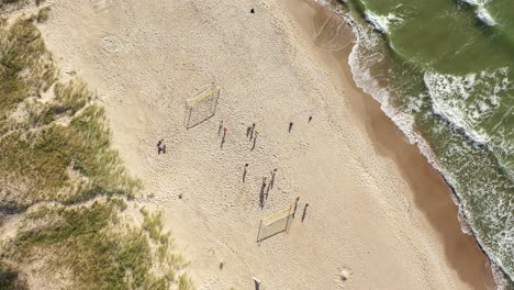 AERIAL:-Top-View-Shot-of-Football-Players-Playing-Ball-on-a-Sandy-Beach