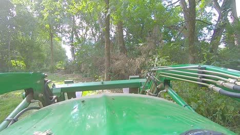 POV-of-equipment-operator-driving-a-loader-with-forks-on-a-trail-thru-the-woods-on-a-sunny-day