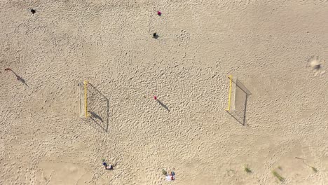 AERIAL:-Symmetrical-Descend-Shot-of-Football-Court-on-a-Sandy-Beach-on-Sunny-Day