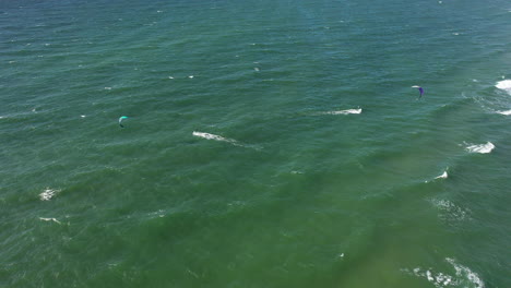 AERIAL:-Locked-Shot-of-Surfers-in-Green-Baltic-Sea-on-Perfect-Sunny-Weather-in-Natural-Daylight
