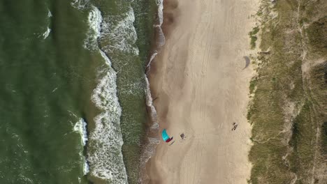 AERIAL:-Top-View-Shot-of-Isolated-Surfer-with-Wind-Kite-Waiting-on-Beach-in-Nida