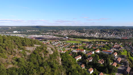 Forward-aerial-drone-above-rocky-mountain-by-residential-suburb-in-east-Gothenburg,-Sweden,-day